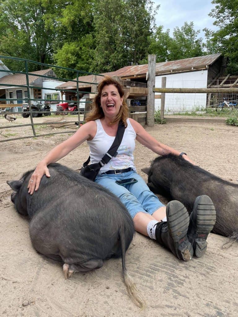 Lori with two pigs at a sanctuary