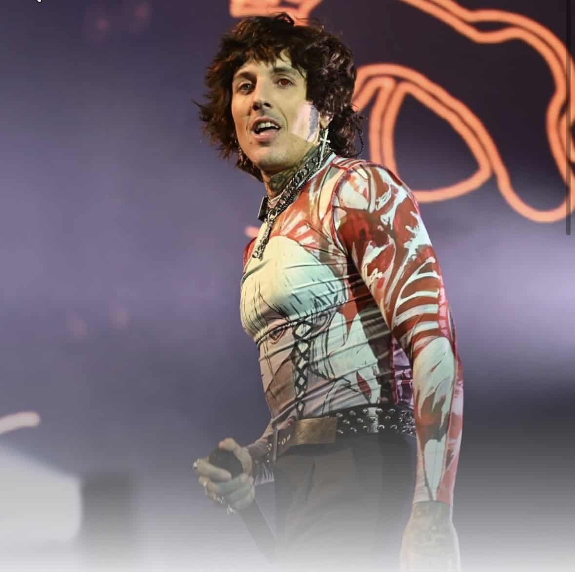 Performer with tattoos on arms and chest, singing passionately on stage at a vegan-themed metal concert. The background features neon lighting, emphasizing the energetic atmosphere promoting animal ri.