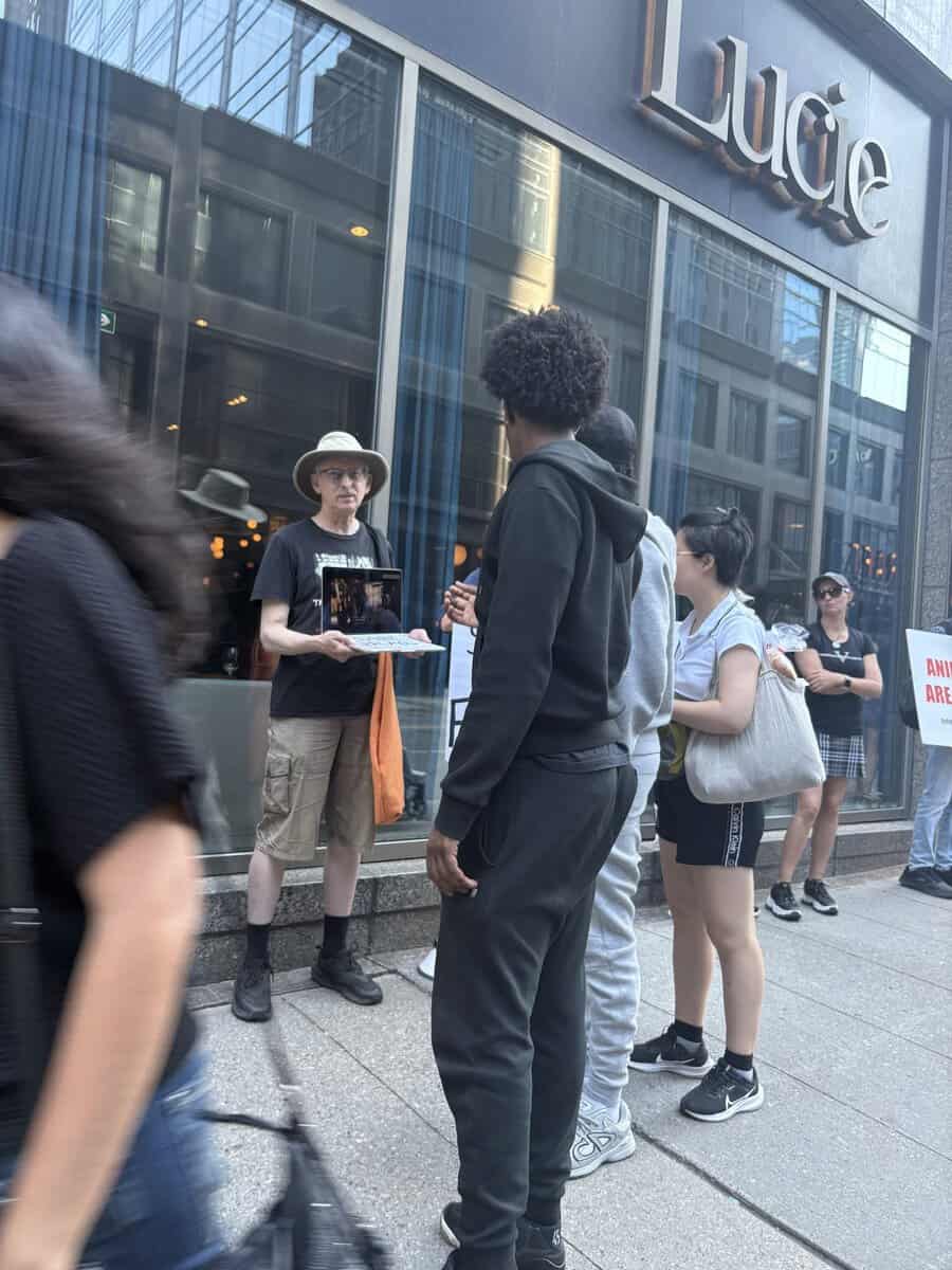 Activists protesting against foie gras outside Lucie restaurant in Toronto, advocating for animal rights and veganism.